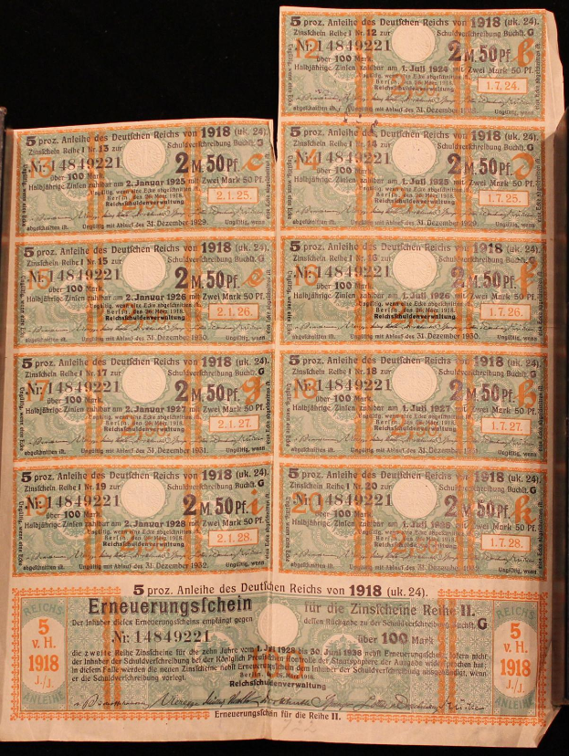 Ein altes Buch mit einem Stapel deutscher Reichsbanknoten von 1918, Nennwerte sichtbar, auf schwarzem Hintergrund.