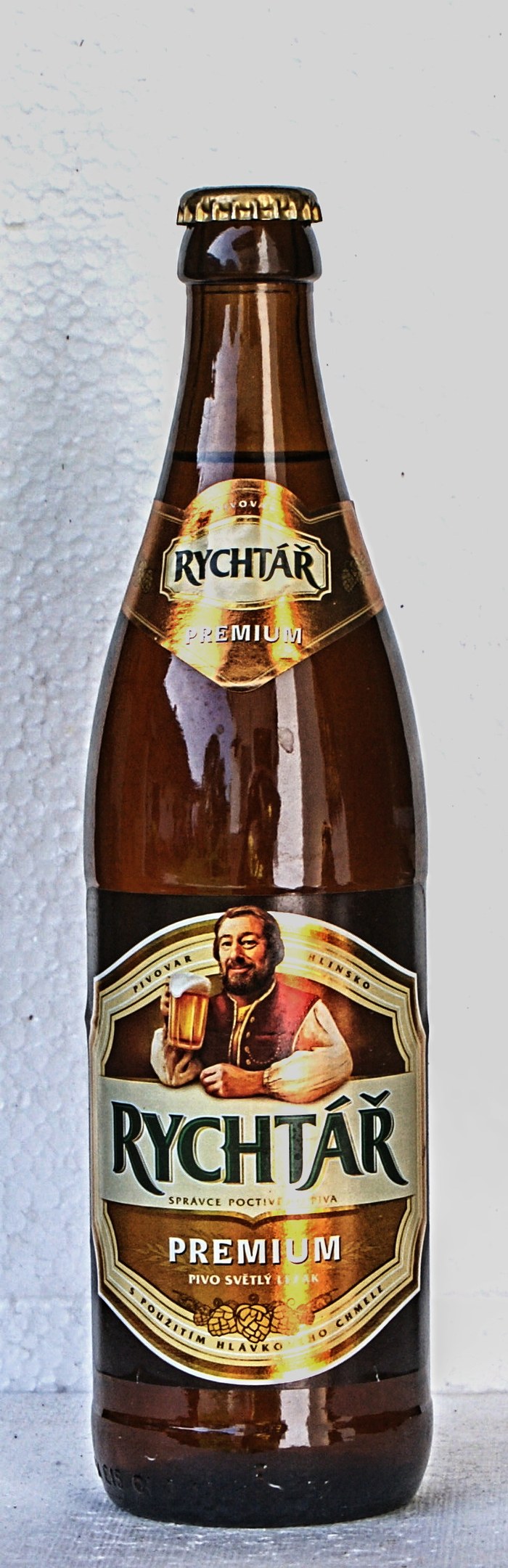 Eine Flasche Rychtar Premium-Bier mit einem Etikett, das ein Bild einer Person und Text zeigt, auf einem Tisch.