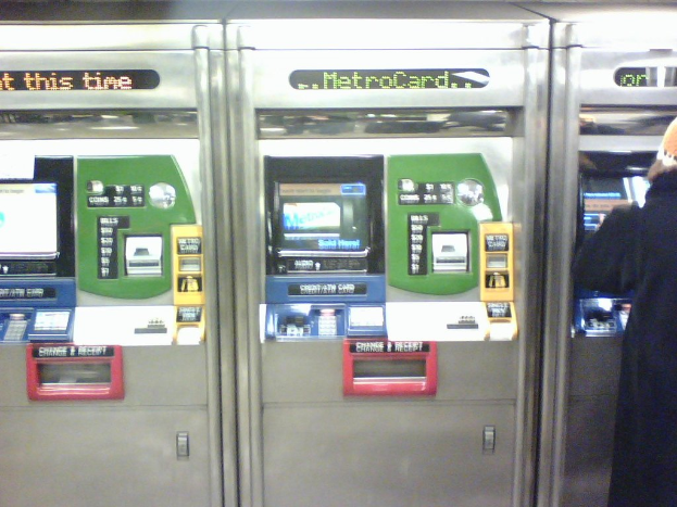 Automatische Ticket-Verkaufsautomaten mit einer Person rechts daneben.