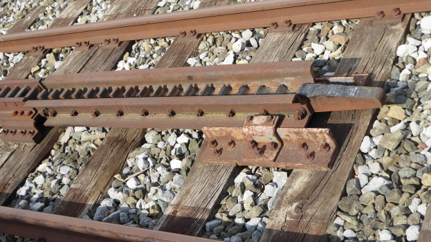 Nahaufnahme einer Schienenstrecke mit Metallschienen und umgebenen Steinen.