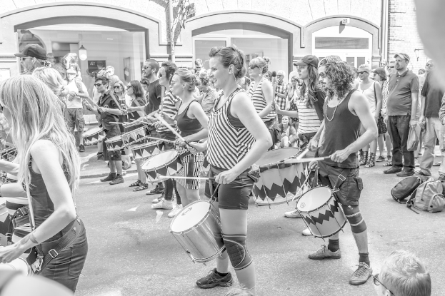 Eine Gruppe von Menschen spielt musikalische Instrumente draußen in der Nähe einer geschlossenen Glastür mit einem Licht.