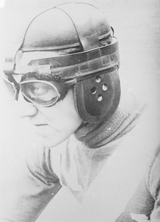 Ein Mann mit Helm und Brille schaut ernst in die Ferne auf einem alten Schwarz-Weiß-Foto.