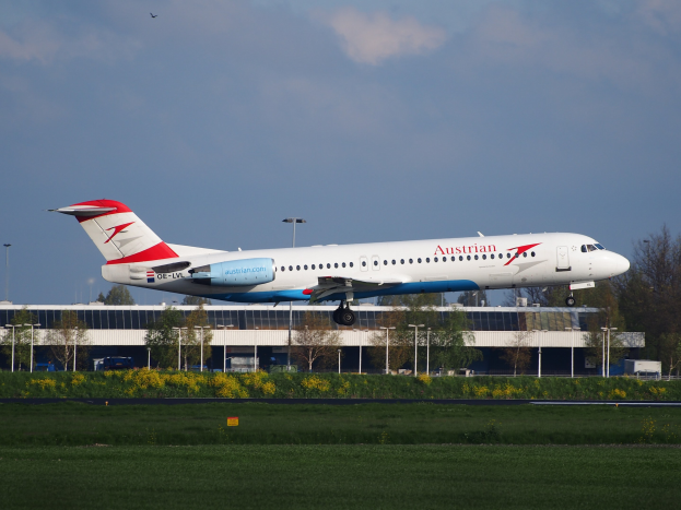 Airbus A320-200 der Austrian Airlines startet von Frankfurt Airport mit Grünfläche, Gebäude und wolkenbedecktem Himmel im Hintergrund.