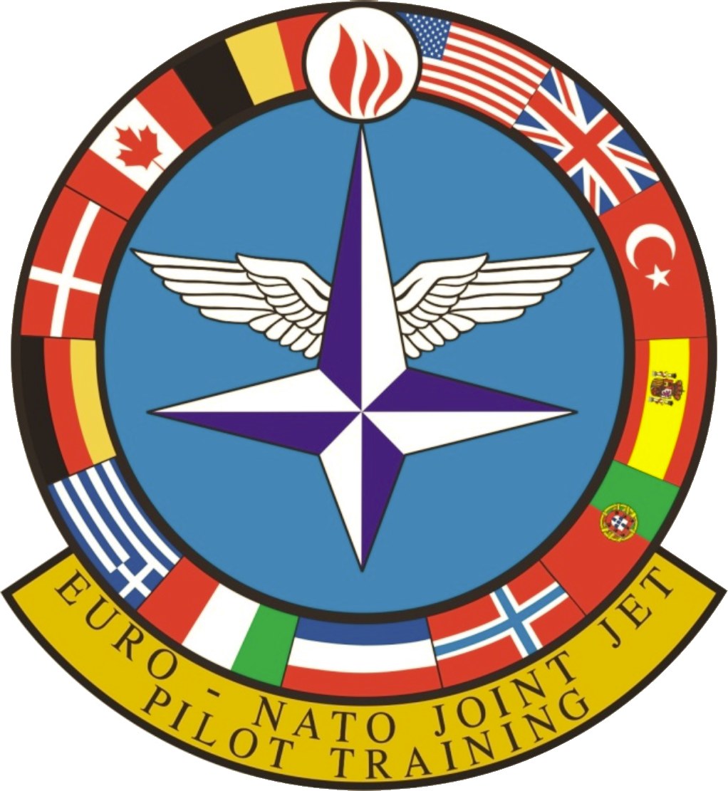 Logo der NATO Joint Jet Pilot Training mit einem blauen Kreis mit einem weißen Stern, umgeben von vier farbigen Flaggen, und der Text 'NATO Joint Jet' in Weiß.