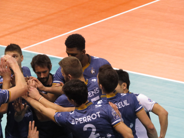 Eine Gruppe von Männern in blauen "Ligue 1" Shirts feiert auf einem Volleyballfeld.