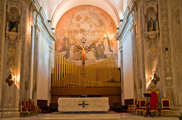 Das Innere einer Kirche mit einer Statue des Jesus Christus in der Mitte und roten Stühlen auf der rechten Seite.