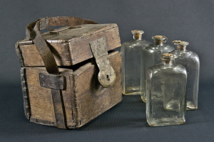 Ein alter Holzkasten mit einem Schloss, der vier durchsichtige Glasflaschen verschiedener Größen enthält, wahrscheinlich zum Aufbewahren von Medizin.