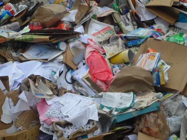 Ein Stapel Kartons mit verschiedenen Gegenständen wie Papieren, Flaschen und Deckeln.