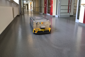 Ein Roboter zum Reinigen von Böden steht auf dem Boden eines Gebäudes, umgeben von Wänden, Türen, Lampen und anderen Gegenständen.