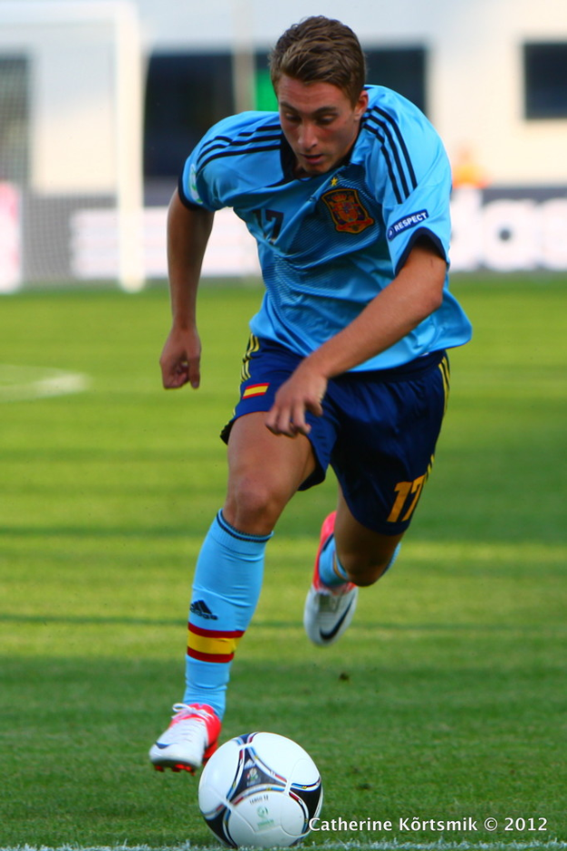 Ein Mann in einem blauen T-Shirt spielt Füßball auf einem Feld.