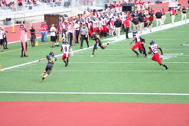 Menschen in schwarzen und weißen Uniformen, die auf einem Feld einen Sport ausüben, mit Zuschauern und Kameraleuten im Hintergrund.