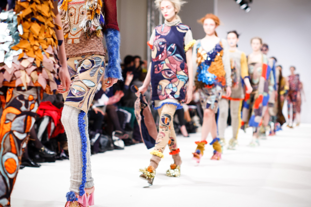 Eine Gruppe Von Frauen Geht Den Laufsteg Runway Down Bei Der London Fashion Week, Mit Sitzenden Zuschauern Und Bühnenbeleuchtung Im Hintergrund.