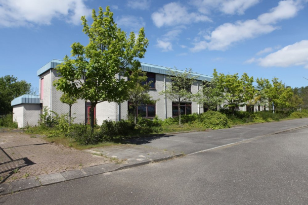 Ein industrielles Objekt zum Verkauf im St. Johns Business Park, umgeben von Bäumen, Pflanzen und Gras, mit einer bewölkten Himmel