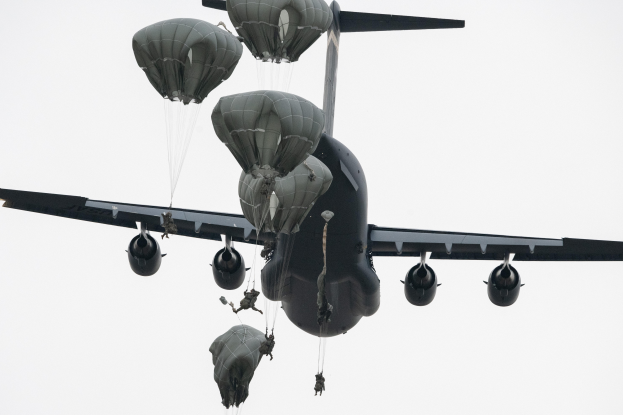 Großes Militärflugzeug mit mehreren Fallschirmen im klaren blauen Himmel