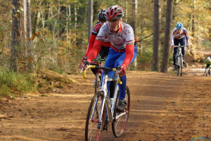 Menschen radeln auf einer Straße mit Bäumen im Hintergrund.
