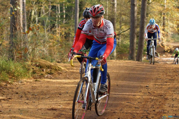 Menschen radeln auf einer Straße mit Bäumen im Hintergrund.