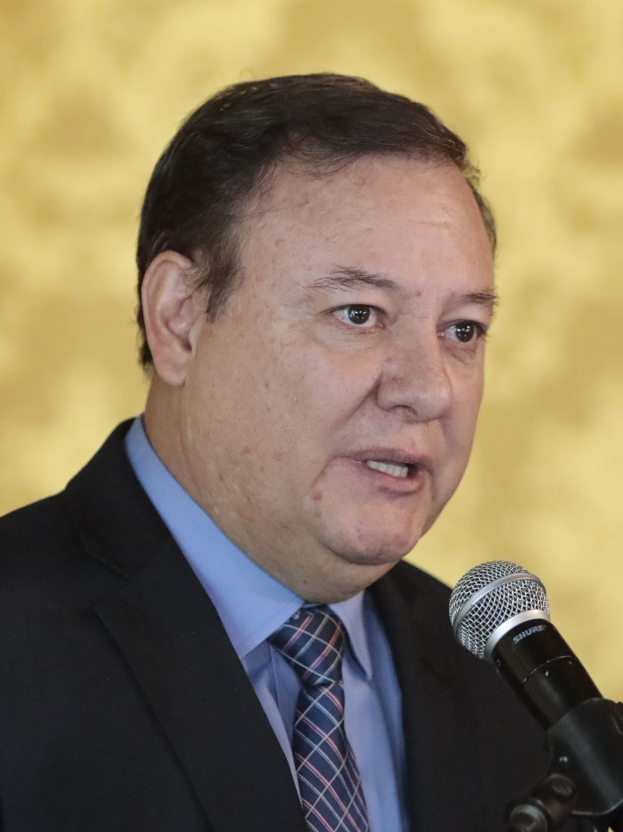 Ein Mann im Anzug und mit Krawatte, der als Generalstaatsanwalt identifiziert wird, spricht in ein Mikrofon mit einem unscharfen Hintergrund.