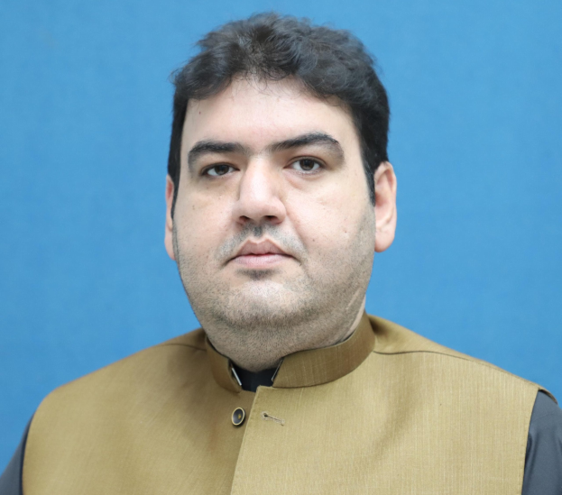 Ein Mann in einer braunen Weste und schwarzem Hemd steht vor einem blauen Hintergrund und scheint über seine lebenslange Haftstrafe nachzudenken.