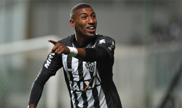 Ein Fußballspieler in einem schwarzen und weißen gestreiften Trikot feiert mit einem Lächeln nach einem Tor