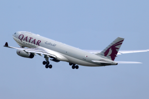 Ein Airbus A330-300-Flugzeug der Qatar Airways mit weißer und roter Lackierung, das durch einen blauen Himmel fliegt, die Flügel weit ausgebreitet.