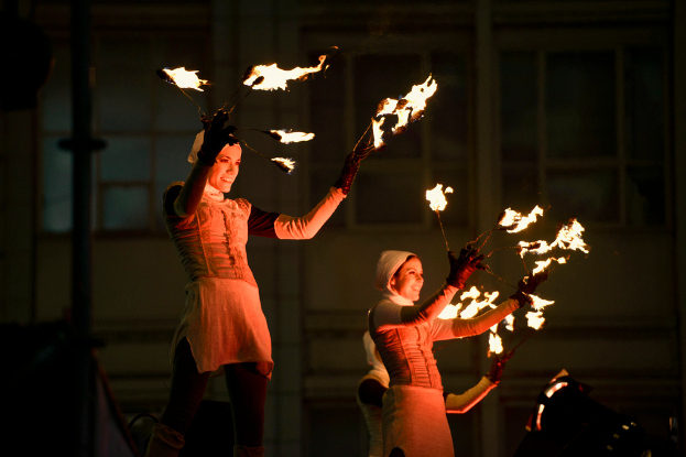 Eine Gruppe von Menschen mit Feuerstöcken steht vor einem Gebäude.