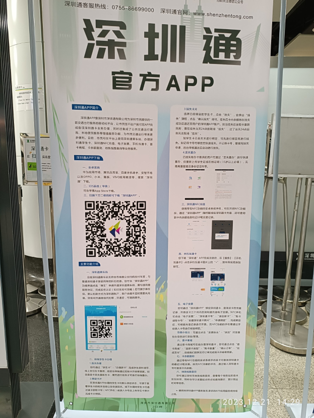 Eine Fahne mit einem QR-Code vor einem Gebäude, wahrscheinlich Werbung für den Shenzhen International Airport, umgeben von Ständen und Schildern.