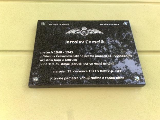 Schwarze Plakette mit weißer 'Jaroslav Chmelik'-Beschriftung in dekorativem Rahmen, an der Gebäudewand montiert.
