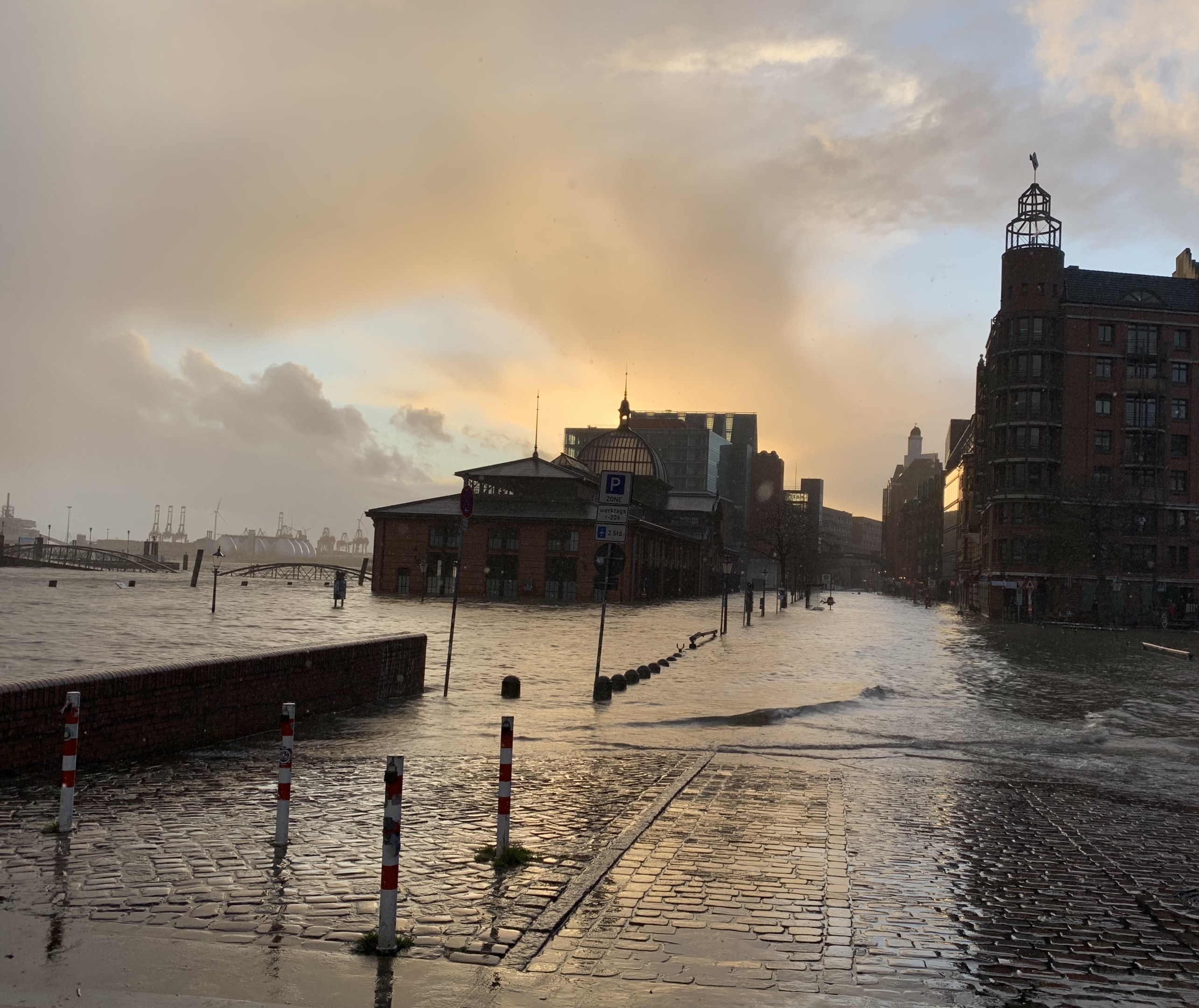 Überschwemmte Straße in Hamburg, Deutschland mit Wasser bedeckten Straße, Polen, Schilder, Gebäude, Brücke unter einem bewölkten Himmel.