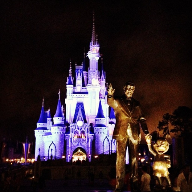 Statuen auf der rechten Seite des Bildes mit einem Cinderella-Schloss im Hintergrund und sichtbaren Bäumen.