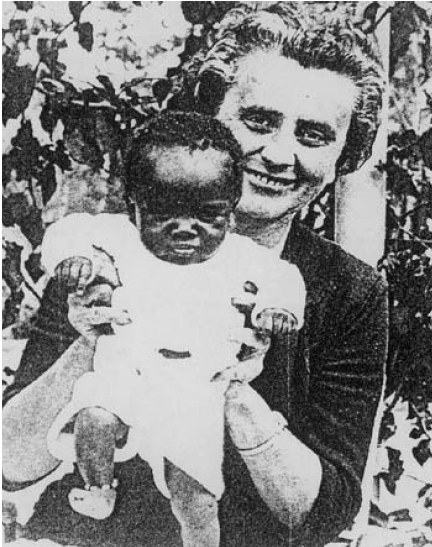 Ein Schwarz-Weiß-Foto einer Frau, die strahlend ihr Baby hält, mit Blättern im Hintergrund