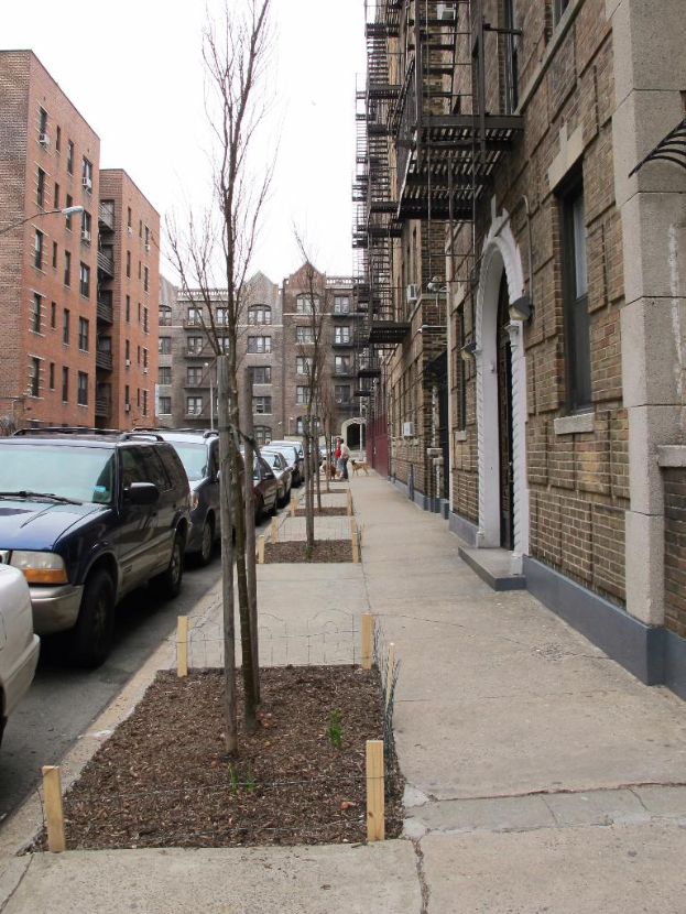 Eine spörliche Stadtlandschaft mit wenigen Autos und Geböuden in der rechten Ecke und einigen anderen Geböuden in der linken Ecke.