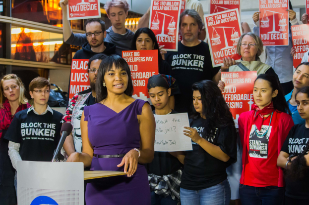 Eine Black Lives Matter-Aktivistin spricht vor einem Publikum mit Mikrofon, das Plakate hält.