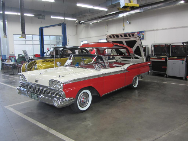 Eine Szene Mit Fahrzeugen Auf Der Rechten Und Einem Tisch Mit Stühlen Und Verschiedenen Gegenständen Auf Der Linken.