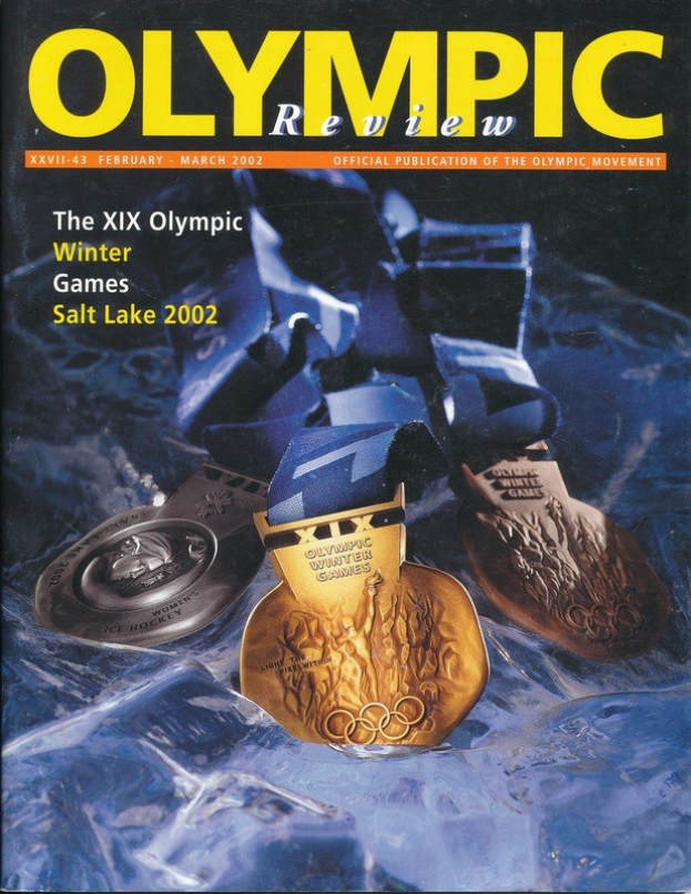 Buchumschlag des *Olympischen Review Magazins* mit mehreren Medaillen in verschiedenen Größen und Farben und fetter Schrift.