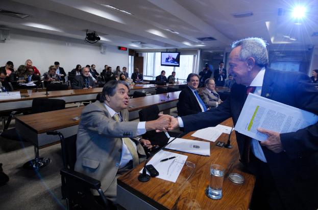 Eine Gruppe von Menschen ist in einem Raum in ein Gespräch vertieft, während andere im Hintergrund sitzen und eine Decke mit Lampen zu sehen ist.