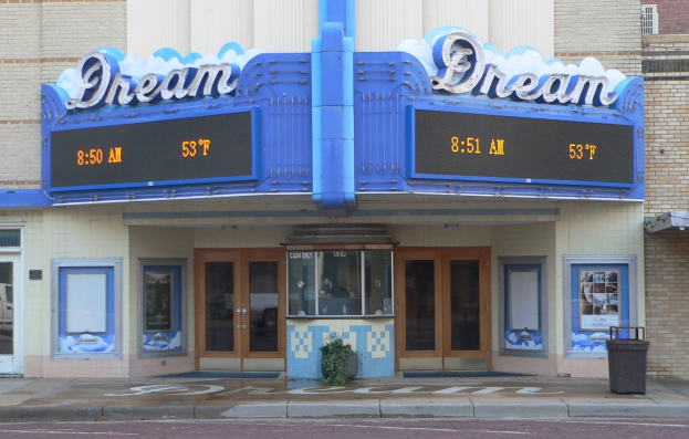 Außenansicht des Dream Theaters in St. Louis, Missouri, mit Glastüren und -fenstern, einem Namensschild, einem Müllcontainer, einem Topf mit einer Pflanze und einer Straße im Vordergrund.