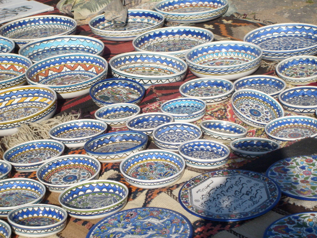 Eine Sammlung von Decken mit Schüsseln und Tellern darauf, umgeben von Rahmen und weiteren Decken, mit einem sichtbaren Boden darunter.