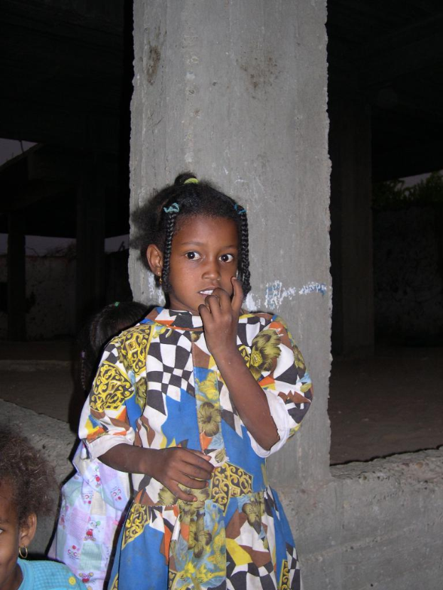 Drei Kinder vor einem Baugerüst mit dunklem Hintergrund.