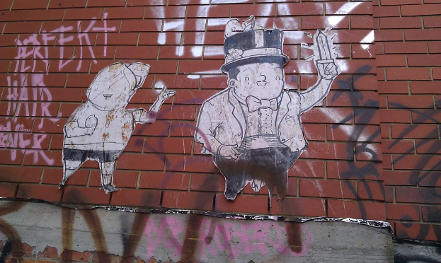 Eine Backsteinwand mit verschiedenen Plakaten und Graffiti.