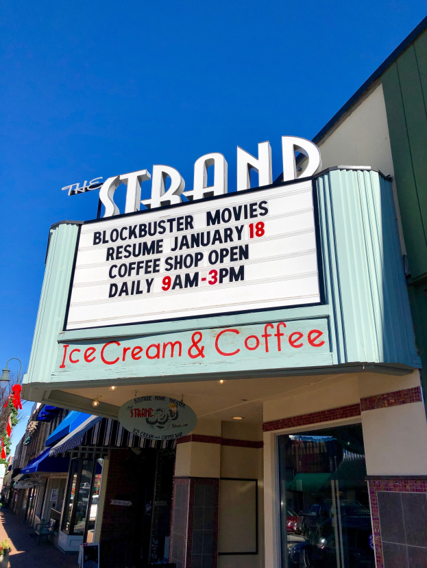 Der Strand-Blockbuster-Kino startet am 18. Januar im Kaffee-Shop-Gebäude mit einem Namensschild, einem Straßenpfosten, einer Gruppe von Bäumen, Topfpflanzen und einem bewölkten Himmel.