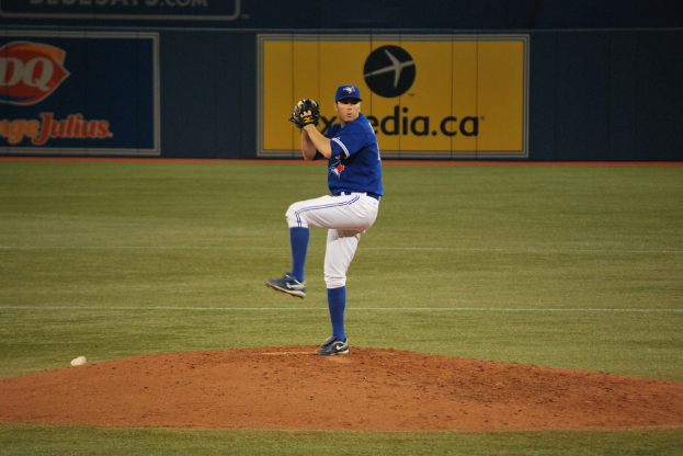 Ein Spieler steht auf dem Boden und hält einen Ball, mit einem großen Banner im Hintergrund mit Text und Bildern.