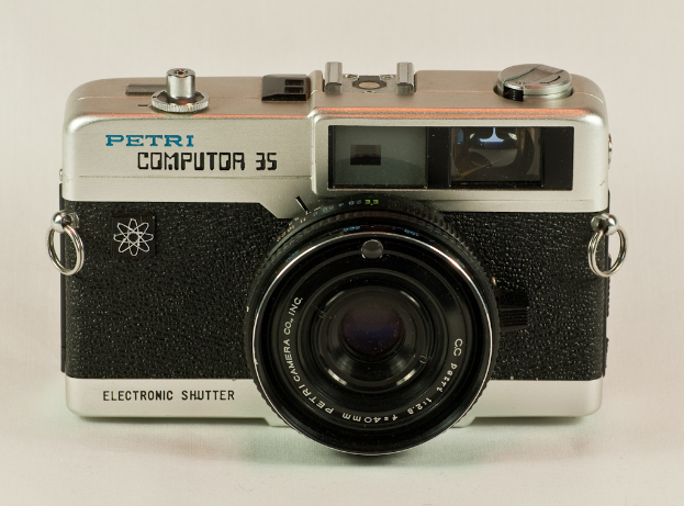 Eine silberne und schwarze Kamera mit der Aufschrift "Petri Computer 35" auf einer weißen Oberfläche.