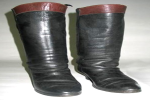Schwarze Stiefel mit roten Schnürsenkeln und Sohlen auf einer weißen Oberfläche, mit einem glänzenden Lederobermaterial, gerundeter Zehe und niedrigem Absatz.