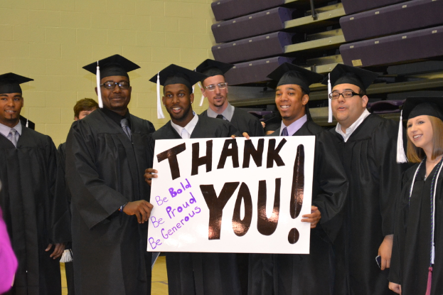 Eine Gruppe von Menschen steht in einer Reihe in der Mitte des Bildes, jeder hält ein Plakat mit der Aufschrift "danke"
