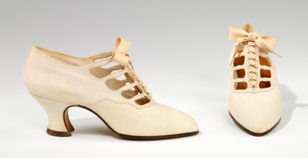 Weiße, spitz zulaufende Pumps mit niedrigen Absätzen und Schleife auf weißem Hintergrund.