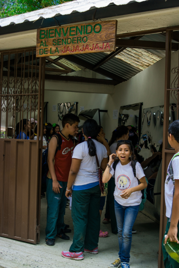 Ein Geschäft mit einem Eisenblechdach und einer Tafel mit Text oben, mit Menschen drinnen.