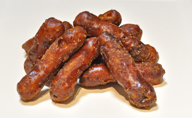 Ein Haufen tiefbrauner, frisch gekochter Würste auf einem weißen Tisch.