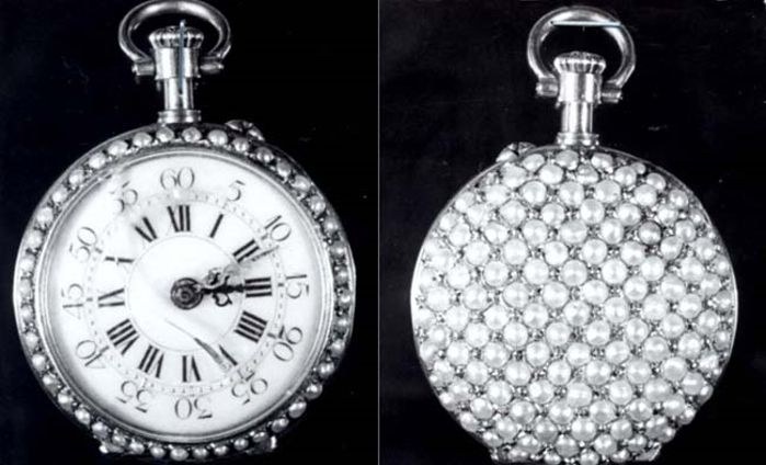 Eine silberne Taschenuhr mit Diamanten, die auf einem schwarzen Hintergrund eingelassen sind, mit einem runden Zifferblatt mit römischen Zahlen.