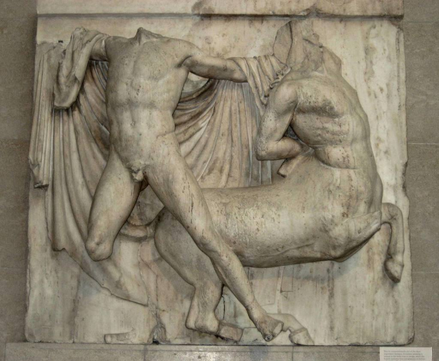 Skulpturen an einer Wand mit Text am unteren Bildrand.