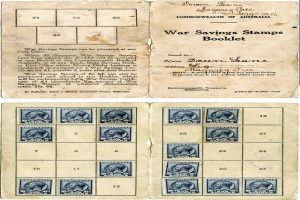 Ein offenes altes Buch mit einer Textseite und Bildern von Menschen, bedeckt mit einer ordentlichen Anordnung von bunten Kriegsanleihestempeln in Rot, Blau, Grün und Gelb.